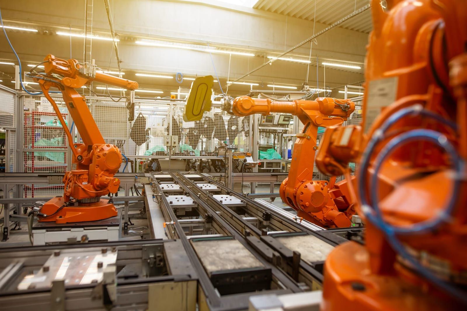 Orange industrial robot arms working along an automated manufacturing line
