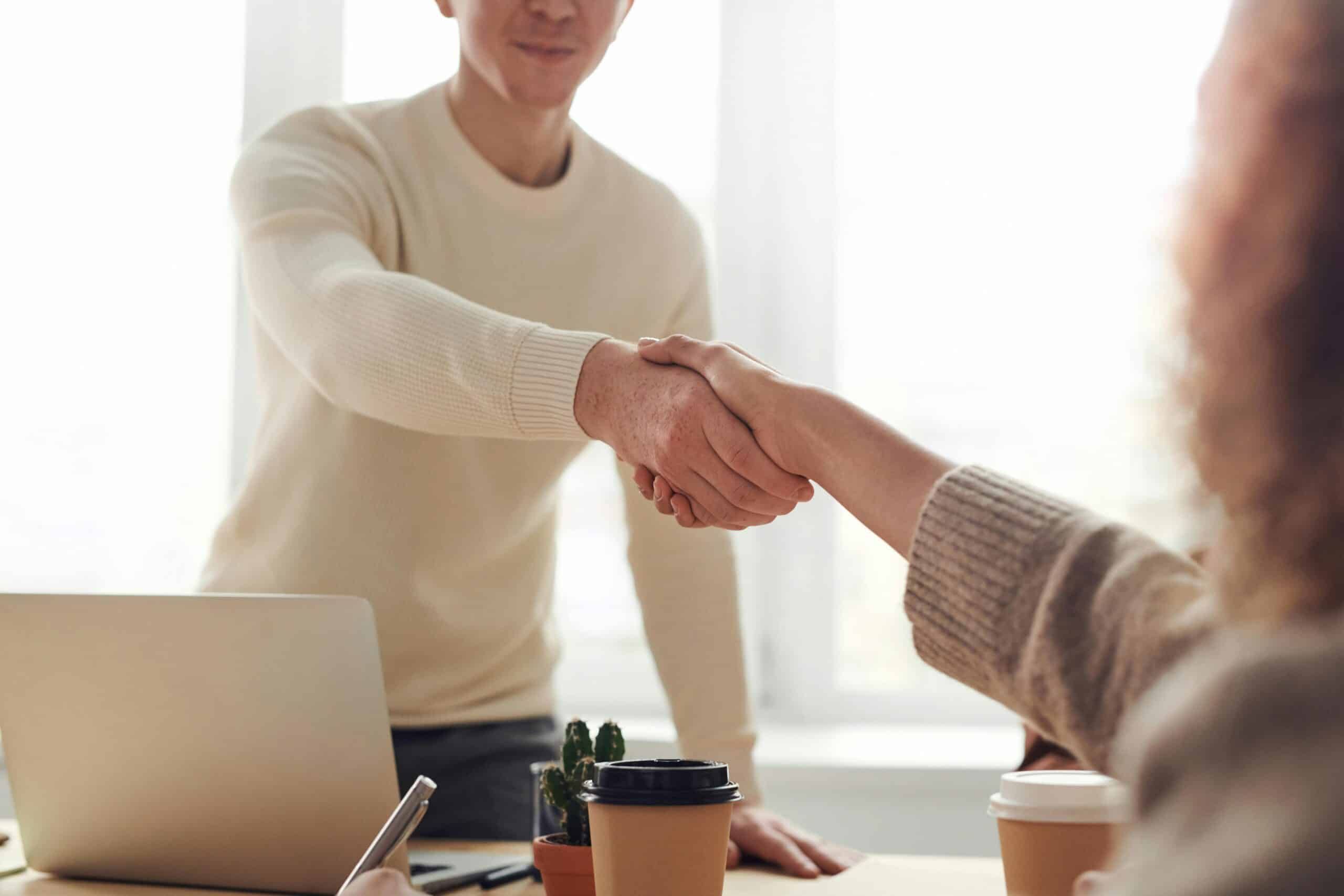 Two people in an office are making an agreement and shaking hands.